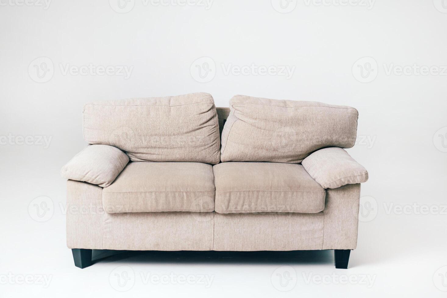 ein grau Sanft Sofa mit Kissen steht im das Mitte von das Zimmer auf ein Weiß Hintergrund. Möbel. Innere. Nahansicht foto