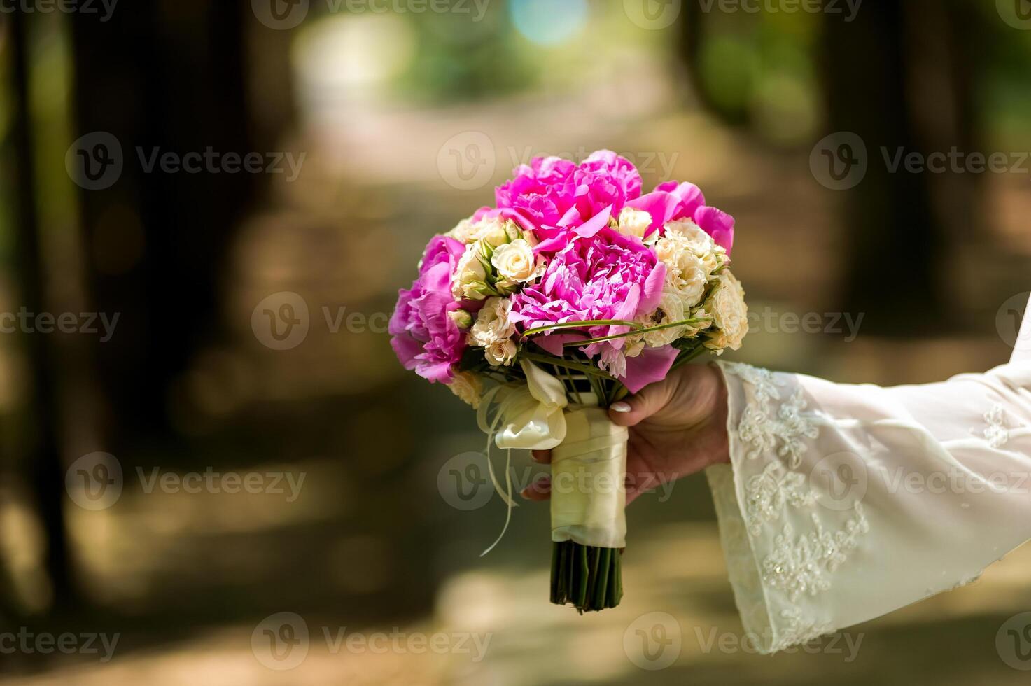 Hochzeit. das Braut im ein Kleid Stehen im ein Grün Garten und halten ein Strauß foto