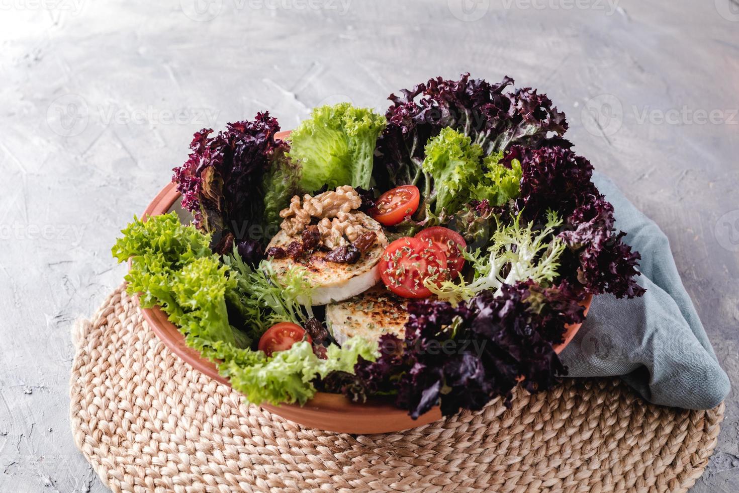 Salat mit Salat, Cherrytomaten, Ziegenkäse, Nüssen und Gewürzen foto