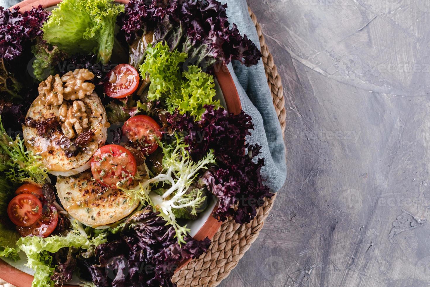 Salat mit Salat, Cherrytomaten, Ziegenkäse, Nüssen und Gewürzen foto