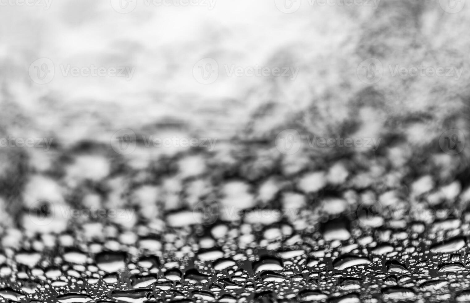 schwarz und Weiß groß Regentropfen auf Glas Oberfläche, klar unten und verschwommen oben im das Bild. natürlich Muster von aqua Tropfen. Makro Aussicht foto