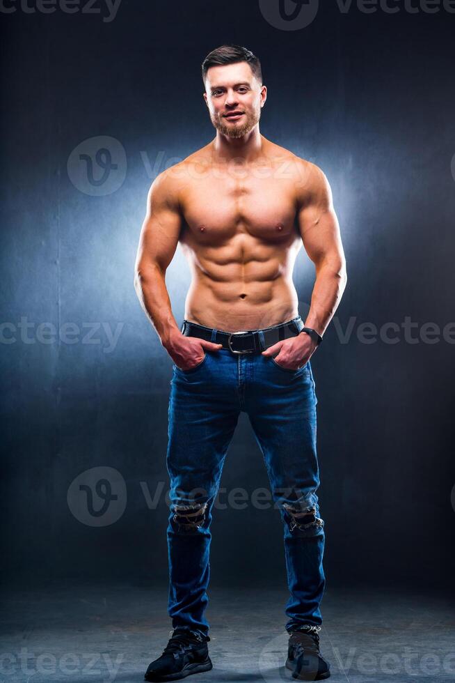 muskulös und passen jung Bodybuilder Fitness männlich Modell- posieren Über dunkel Hintergrund. foto