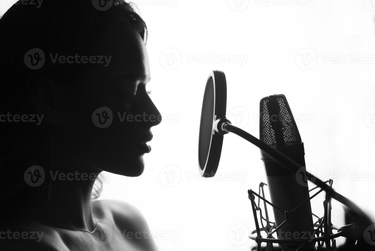 schwarz und Weiß. Frau Singen im das Aufzeichnung Studio. Profil von ein Frau mit ein schön Gesicht und Lippen. foto