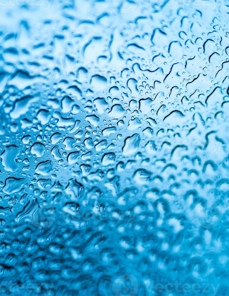 natürlich Wasser Regentropfen auf Glas Fenster nach Regen Über das Blau Hintergrund. abstrakt Textur mit Wasser Tropfen auf Fenster foto