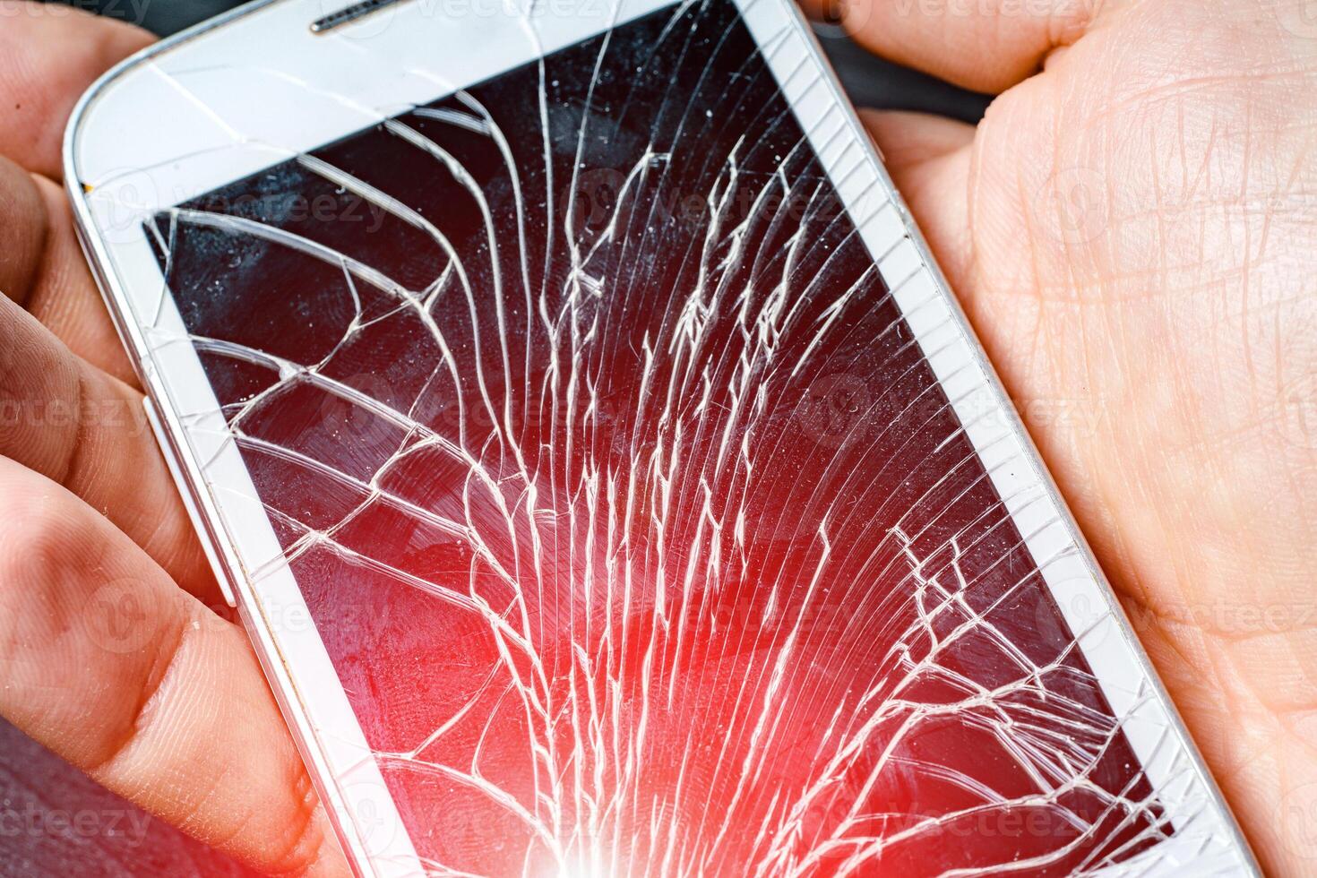 Weiß modern Clever Telefon mit gebrochen berühren Bildschirm isoliert auf männlich Hand mit rot Licht Lecks. des Mannes Hand halten ein geknackt Handy. Nahansicht foto