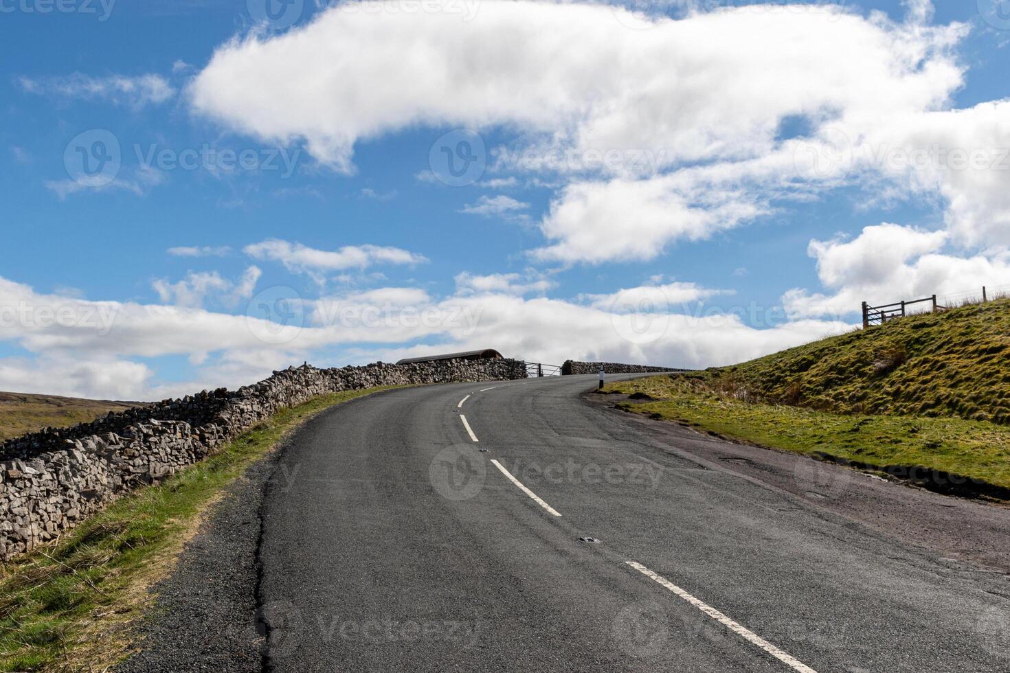 leeren Land Straße mit Stein Wände unter ein Blau Himmel mit Wolken im Yorkshire Täler. foto