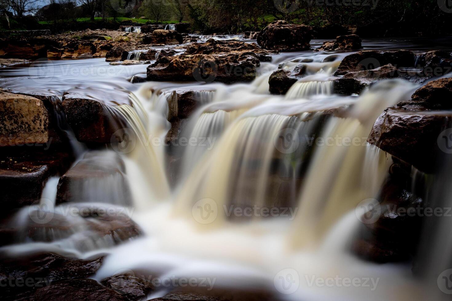 heiter Wasserfall Kaskadierung Über Felsen mit üppig Grün im das Hintergrund, präsentieren der Natur Ruhe im Yorkshire Täler. foto