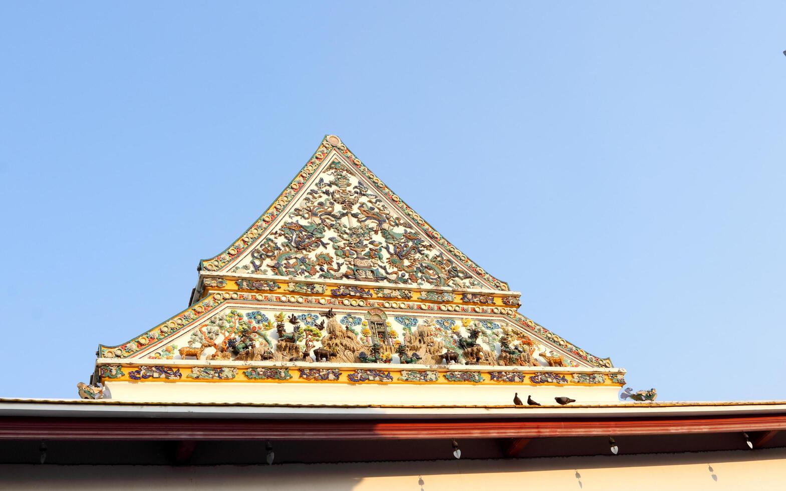 uralt einheimisch Weiß Zement doppelt Niveau gleichschenklig Dreieck gestalten Giebel mit einheimisch Kunst von Buddhismus Kirche und Licht Blau Himmel Hintergrund, Bangkok im Thailand. foto