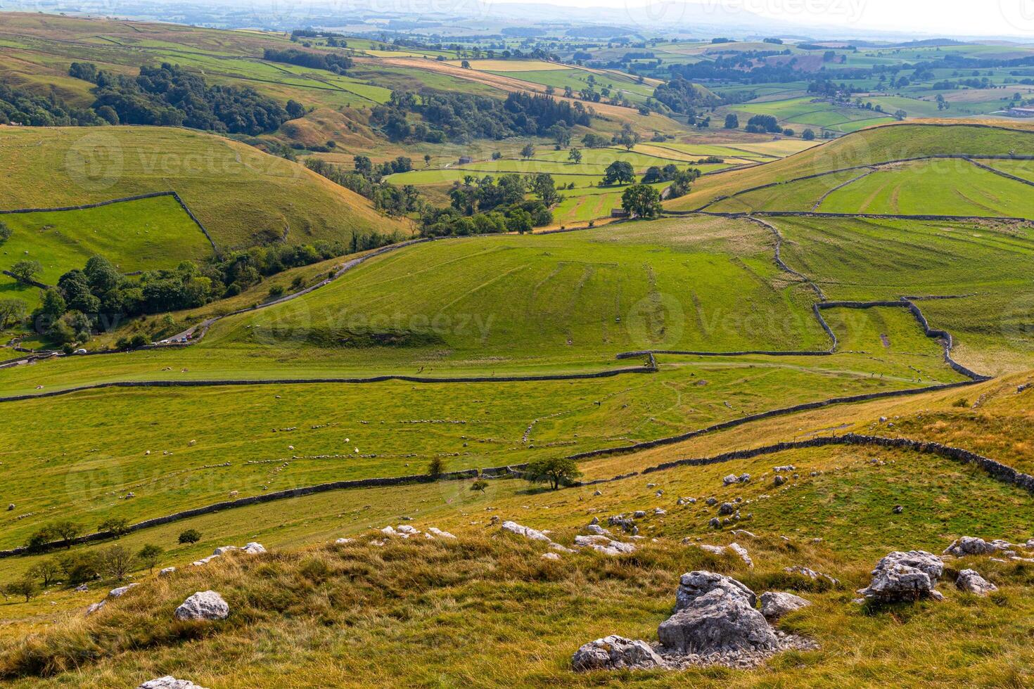 rollen Grün Hügel mit Patchwork Felder und Stein Wände, abbilden ländlich Landschaft Landschaft. foto