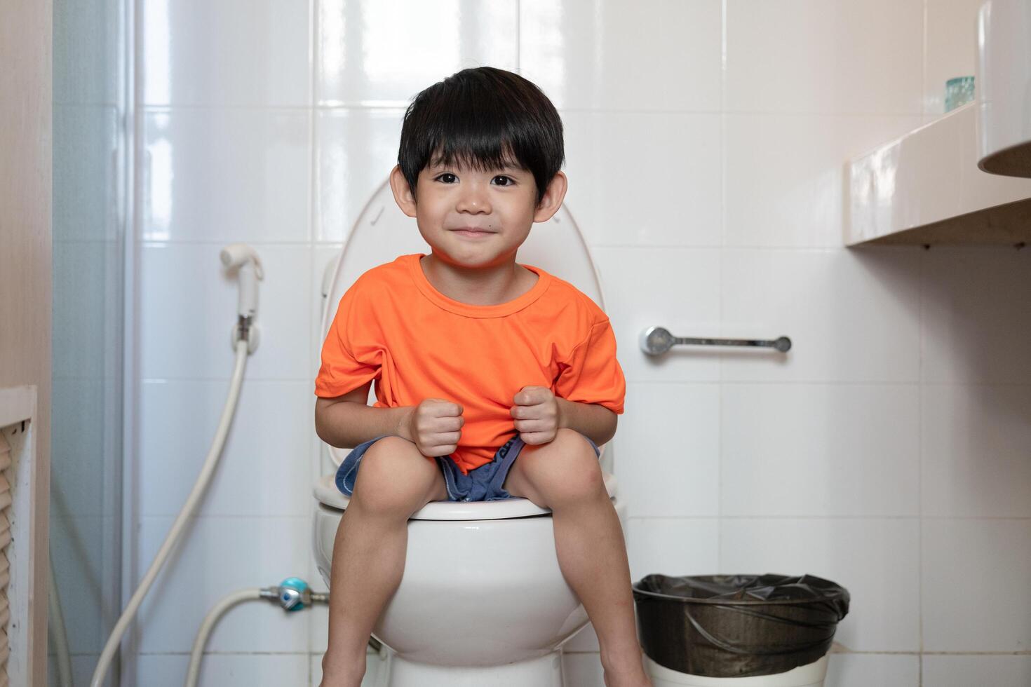 asiatisch Junge Sitzung auf das Toilette Schüssel foto