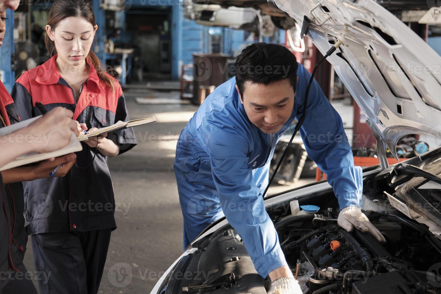 asiatisch männlich Fachmann Automobil Ingenieur Supervisor beschreibt Auto Motor Instandhaltung und Reparatur Arbeit mit Mechaniker Arbeiter Mitarbeiter Mannschaft im Fix Bedienung Garage, Spezialist Berufe im Auto Industrie. foto