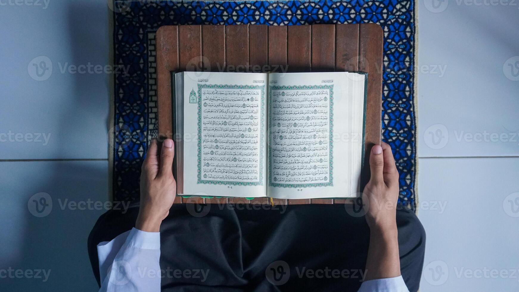 oben Aussicht von ein Muslim Mann lesen das Koran auf ein Gebet Matte foto