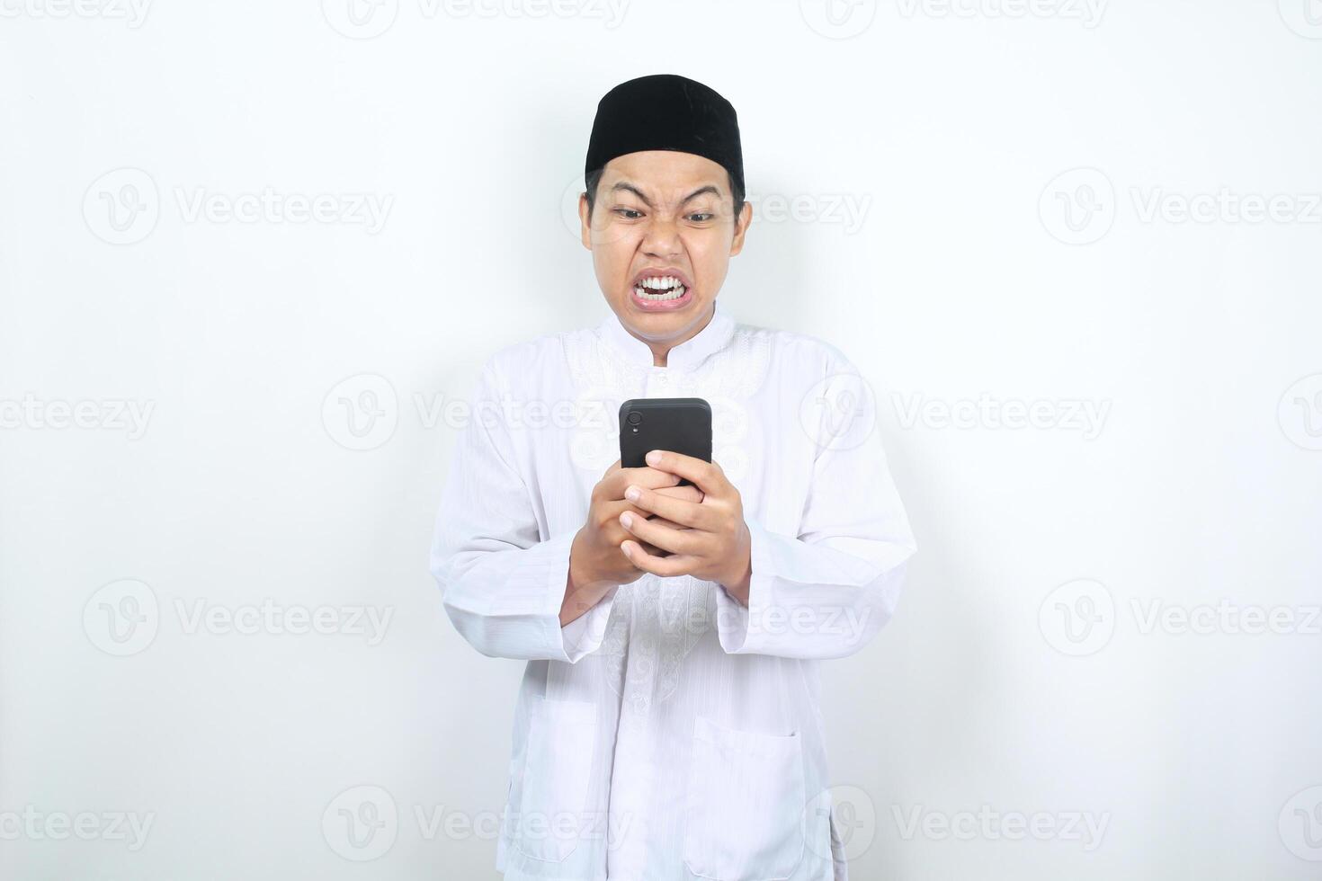 asiatisch Muslim Mann Show wütend Ausdruck während suchen beim seine Telefon foto