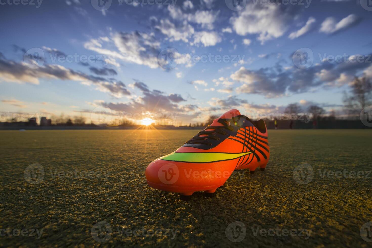 Sport Schuhe auf das Hintergrund von das Feld beim Sonnenuntergang. Fußball Feld mit Turnschuhe foto