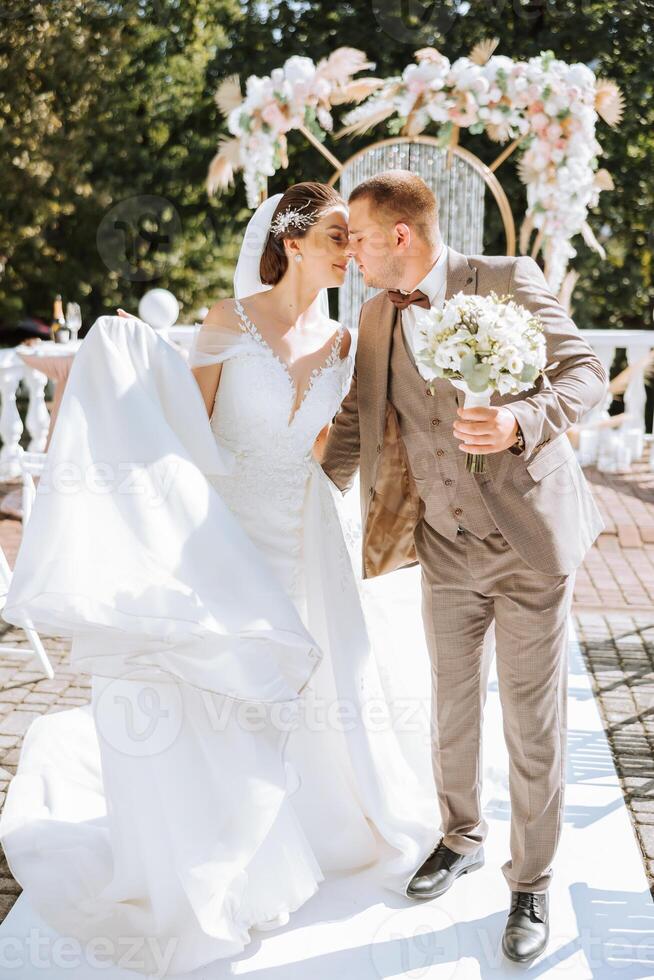 das Braut und Bräutigam sind Gehen gegen das Hintergrund von das Hochzeit Bogen. draussen Hochzeit Zeremonie. Bräutigam und Braut auf das Hintergrund von das Hochzeit Bogen. foto