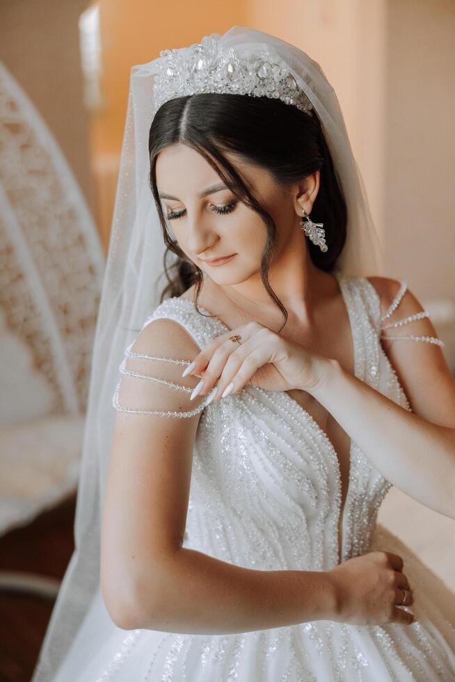 Porträt von das Braut im das Hotel Zimmer. ein schön jung Mädchen ist gekleidet im ein Weiß Hochzeit Kleid. modern Hochzeit Frisur. natürlich bilden. foto