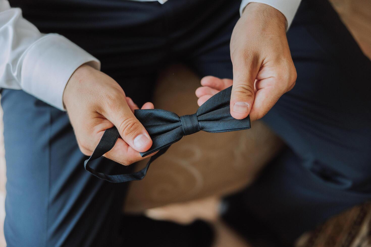 ein bärtig Mann im ein Weiß Hemd passt sich an seine Bogen binden. Bräutigam Morgen. Nahansicht Detail, Herren Krawatte zum ein Hochzeit oder ein wichtig treffen. foto