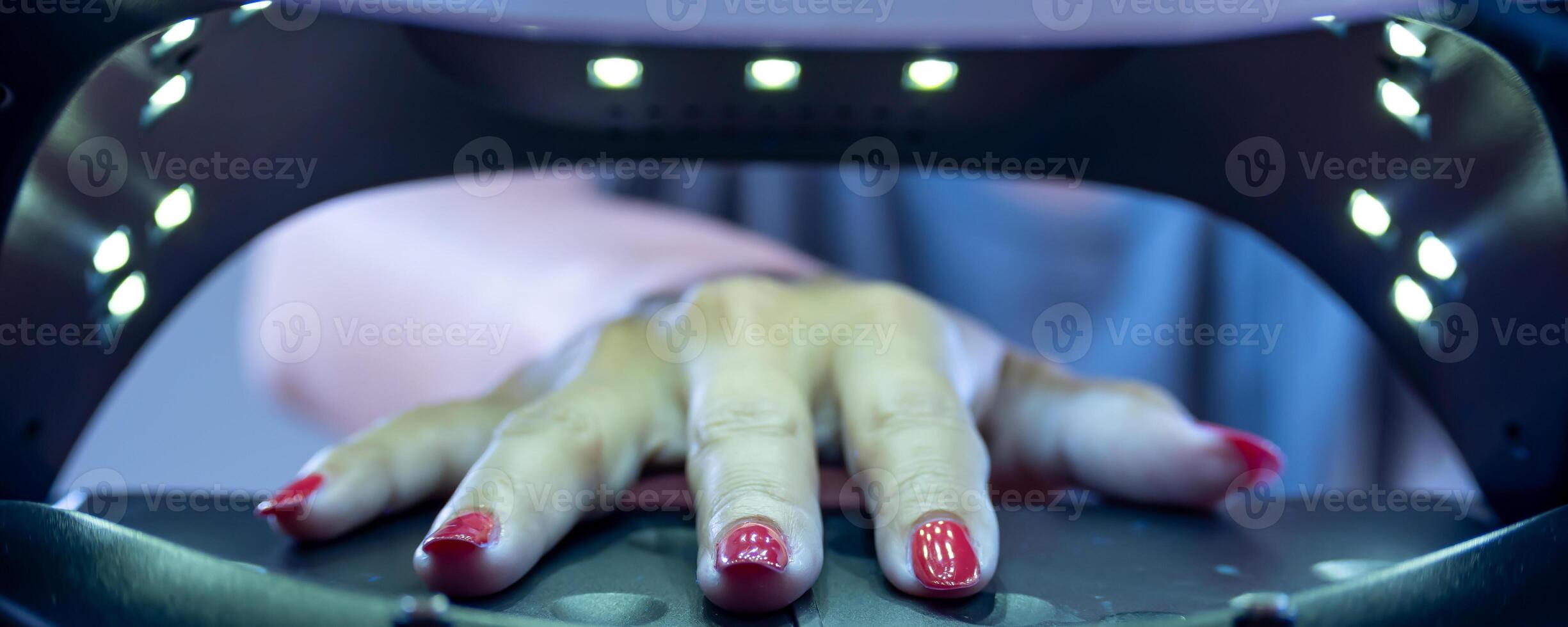 Foto zeigen das Innere von ein ultraviolett Nagel Trocknen Kabinett mit ein jung Frau Hand innen.