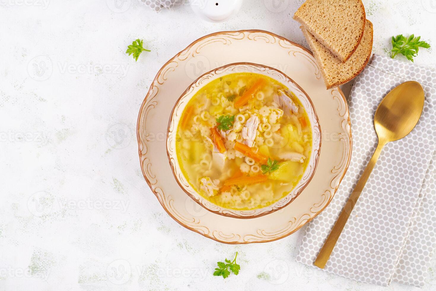 frisch Hähnchen Suppe mit Gemüse und stellin Pasta im ein Schüssel mit Karotte und Petersilie. oben Sicht, eben legen foto