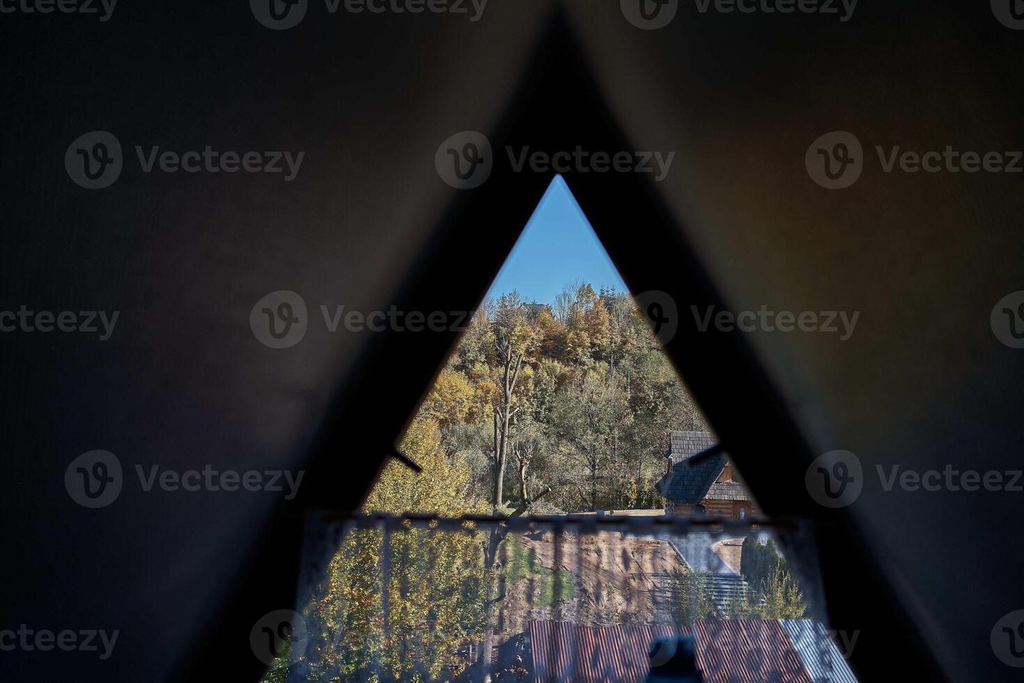 Aussicht von das Herbst Wald durch ein dreieckig Fenster im das Dachboden foto