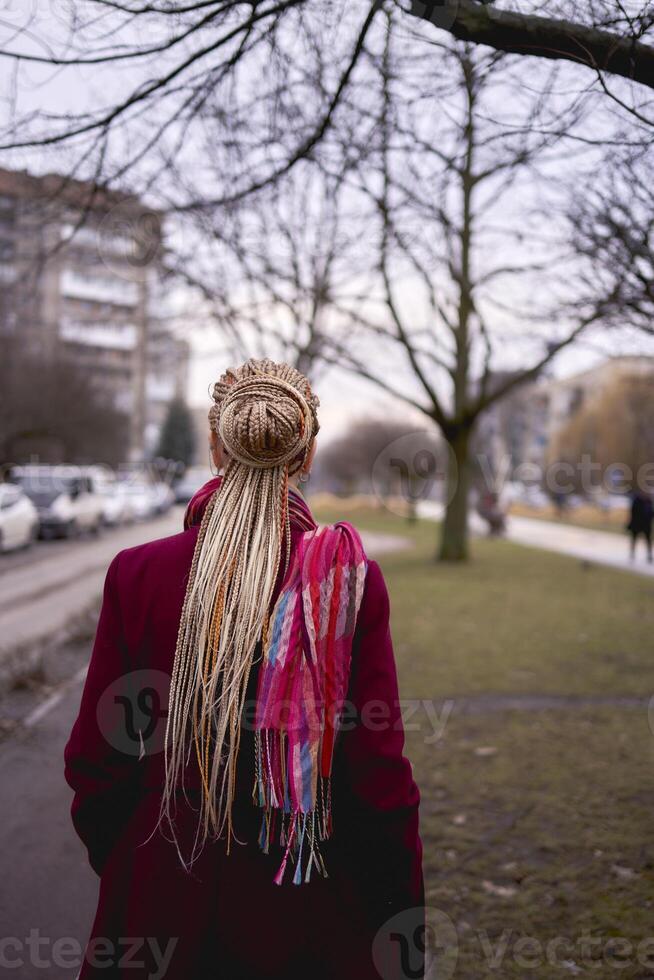 Porträt von ein stilvoll mittleren Alters Frau mit Zöpfe auf ein Frühling Straße foto