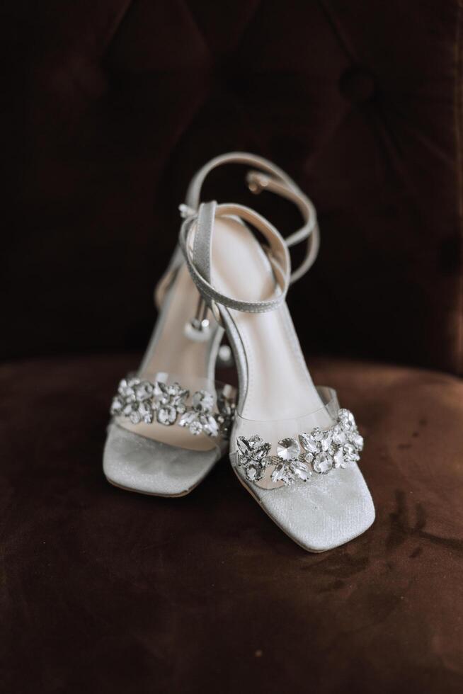 Braut Schuhe. das Mädchen trägt Stilettos. elegant Damen Schuhe. schön Einzelheiten. das Braut setzt auf ihr Schuhe und bereitet vor zum das Hochzeit Zeremonie foto