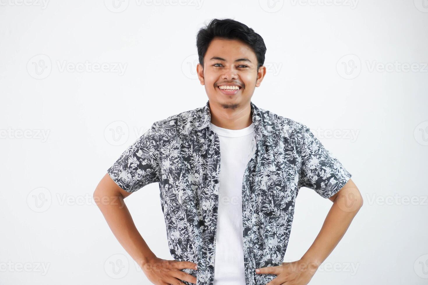 lächelnd oder glücklich asiatisch Mann Hände auf Taille Stehen suchen Kamera isoliert auf Weiß Hintergrund foto