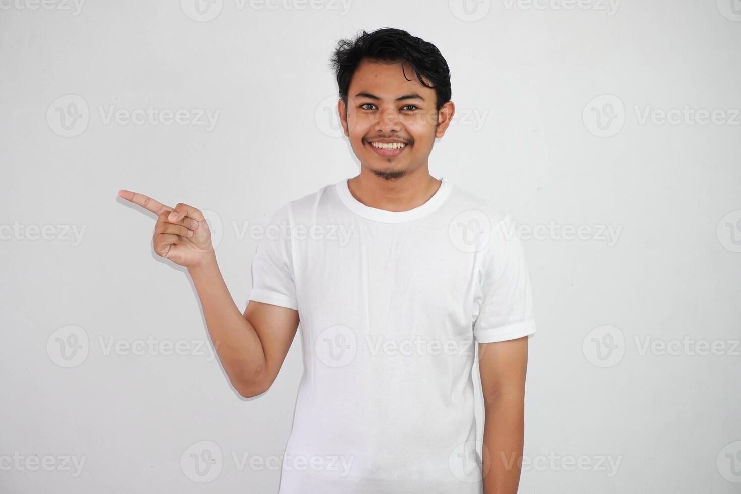 lächelnd asiatisch Mann mit Finger zeigen zu das Seite tragen Weiß t Hemd isoliert auf Weiß Hintergrund foto