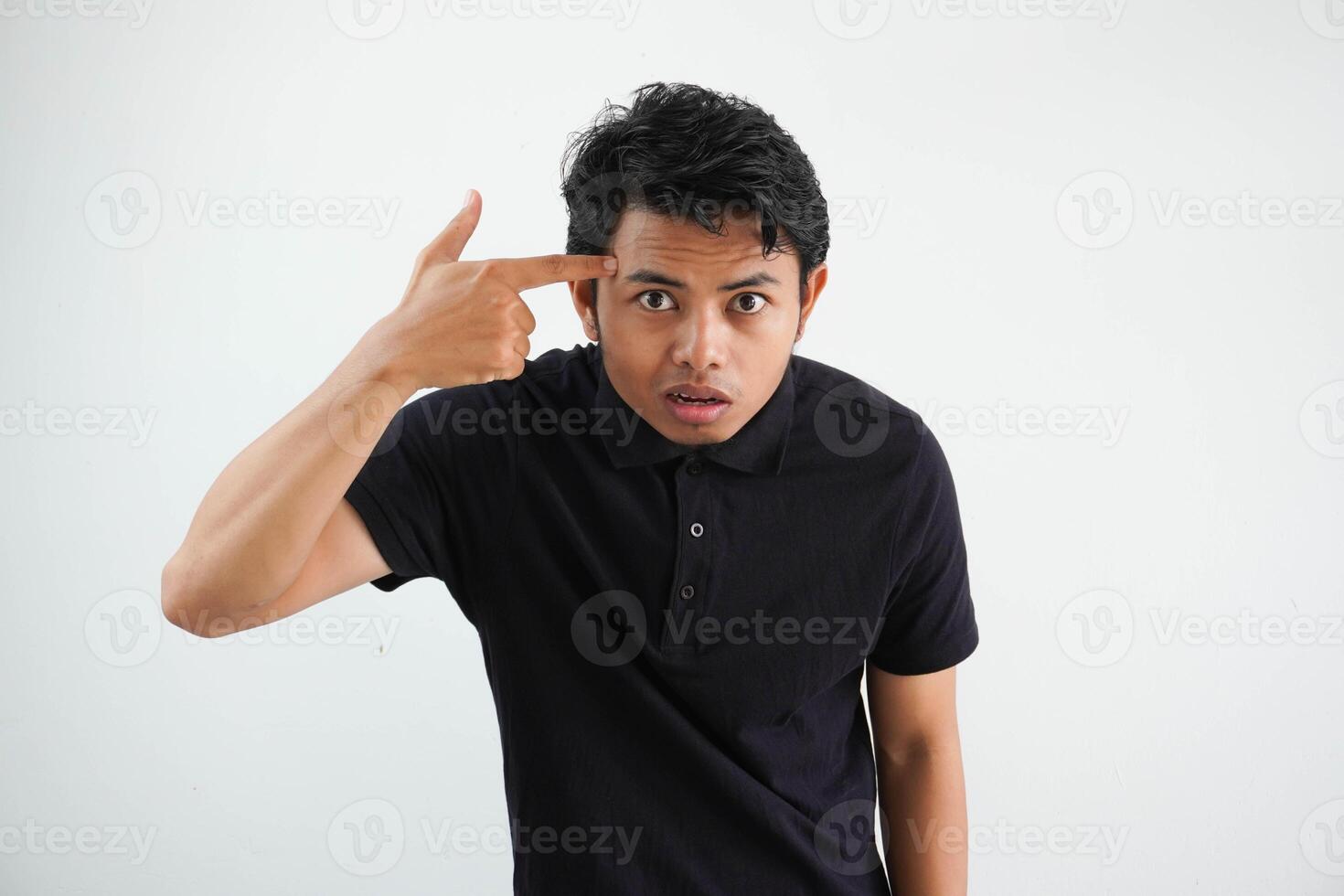 jung asiatisch Mann posieren auf ein Weiß Hintergrund zeigen ein Enttäuschung Geste mit Zeigefinger tragen schwarz Polo t Shirt. foto