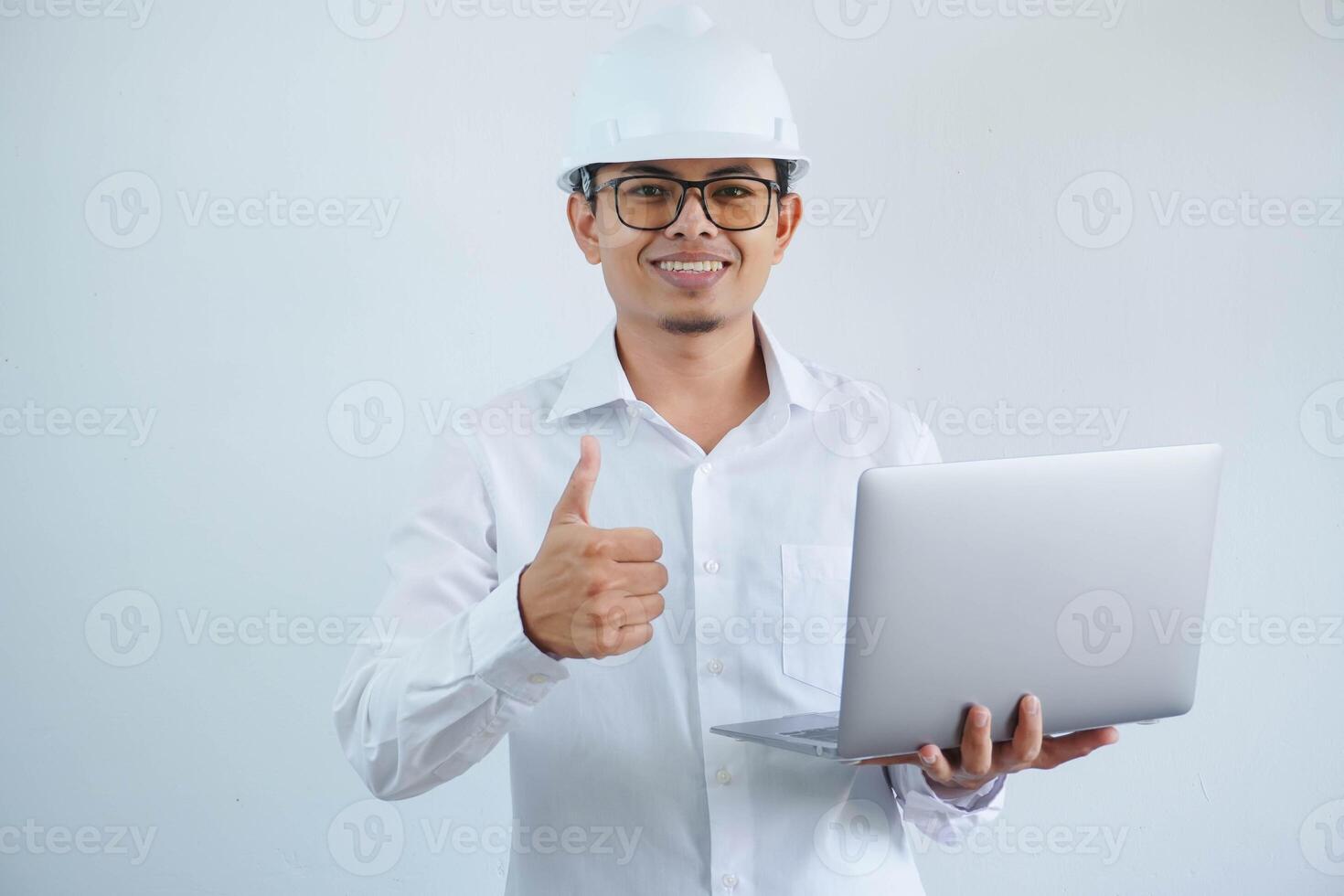 jung asiatisch Architekt Mann tragen Baumeister Sicherheit Helm Über isoliert Hintergrund tun glücklich Daumen oben Geste und halten Laptop mit Hand. foto