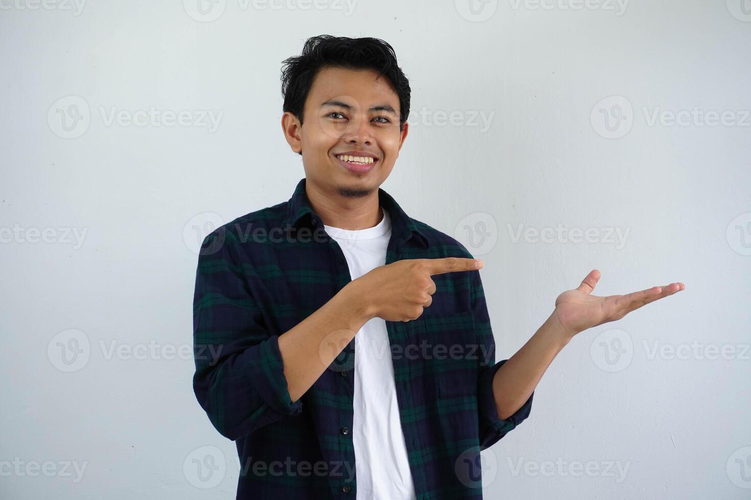 lächelnd jung asiatisch Mann während zeigen zu seine öffnen Hand Palme isoliert auf Weiß Hintergrund foto