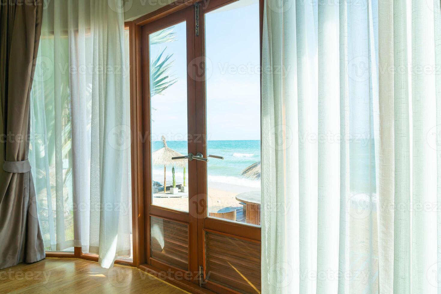 Vorhang und Glasfenster mit Meerblick nach draußen foto
