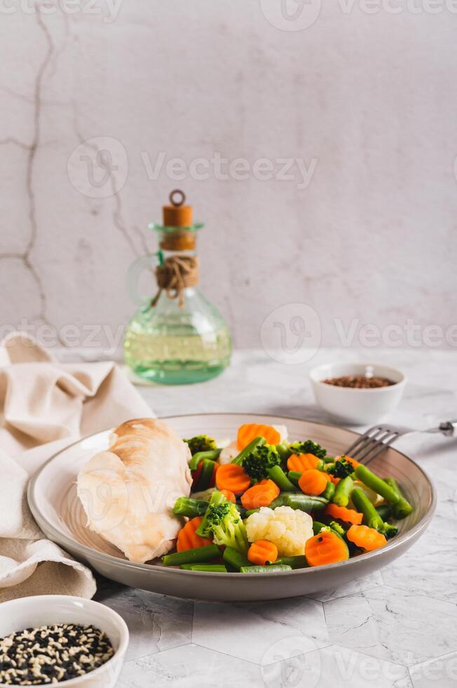 gemischt Gemüse und gedämpft Hähnchen Brust auf ein Teller auf das Tabelle Vertikale Aussicht foto