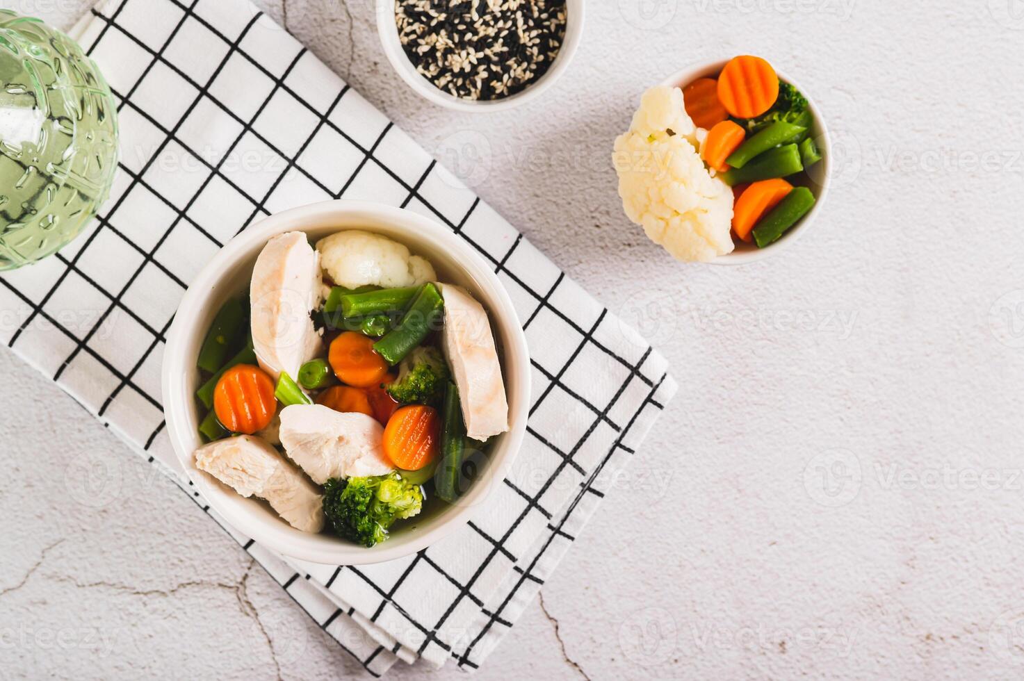 hausgemacht Suppe mit Huhn, Blumenkohl, Brokkoli, Möhren und Grün Bohnen im ein Schüssel oben Aussicht foto