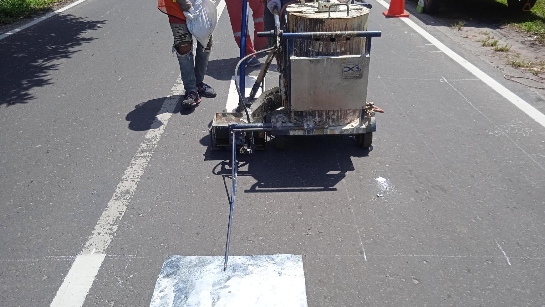 niedrig Sektion von Straße Arbeiter mit thermoplastisch Markierung Maschine foto