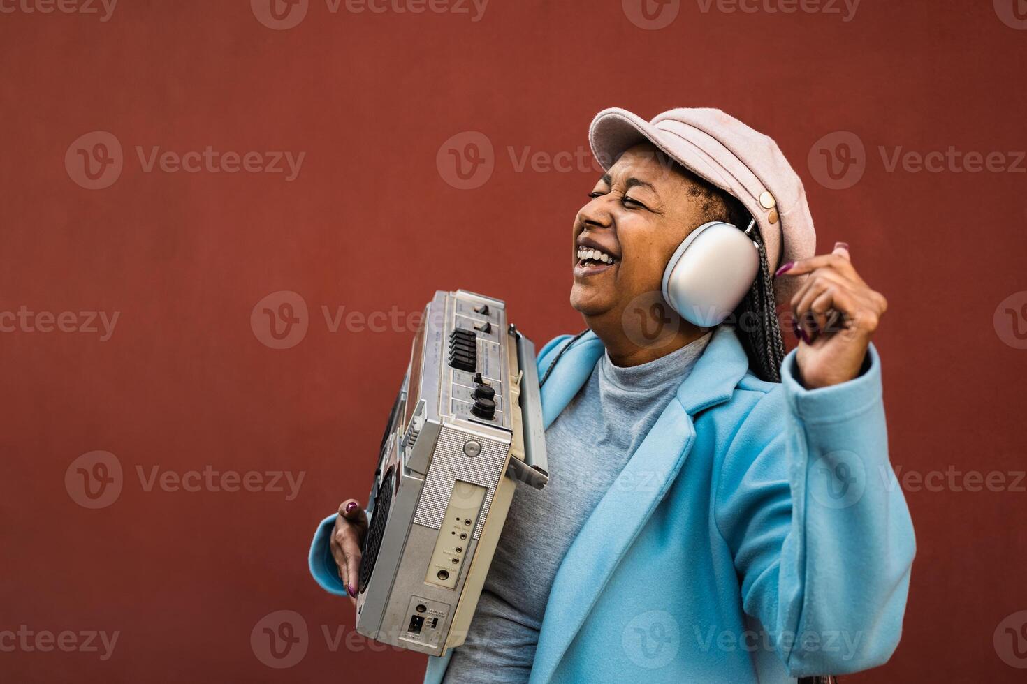 glücklich modisch Senior afrikanisch Frau haben Spaß Tanzen während Hören Musik- mit Kopfhörer und Jahrgang Boombox Stereo foto