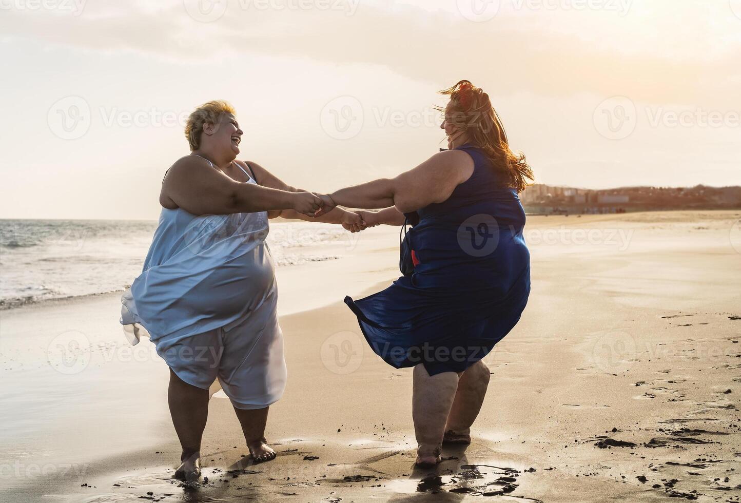 glücklich Plus Größe Frauen Tanzen auf das Strand - - kurvig Übergewicht Mädchen haben Spaß während Ferien im tropisch Ziel - - Über Größe zuversichtlich Menschen Lebensstil Konzept foto