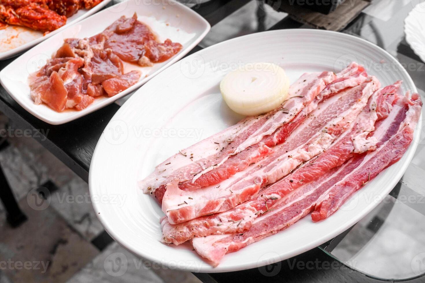 frisch roh Schweinefleisch Bauch gekrönt Rosmarin und schwarz Pfeffer auf das Weiß Teller zum samgyeopsal oder Koreanisch Grill. foto