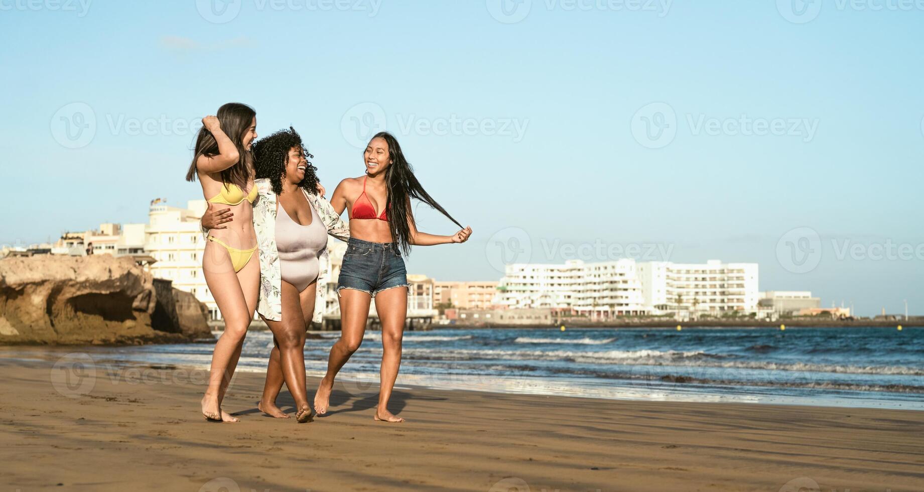 glücklich gemischtrassig Frauen mit anders Körper Größe haben Spaß Gehen auf das Strand während Sommer- Ferien foto
