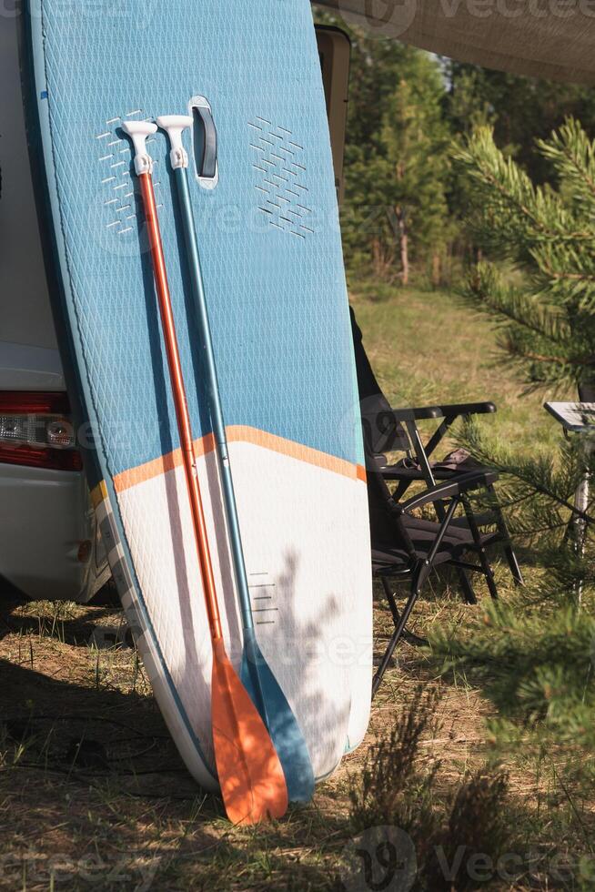 aufblasbar sup Rudern Bretter Stand in der Nähe von das Wohnmobil aufgeblasen im Natur während das Tag foto