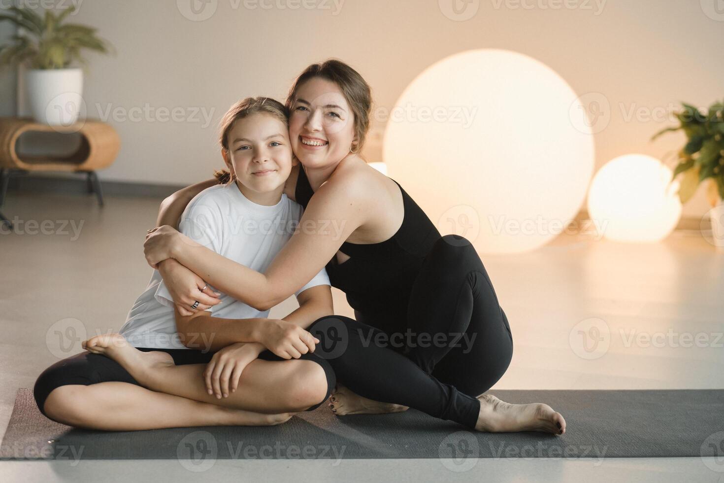 Porträt von ein Mutter und Tochter von ein Teenager im Sport Kleider umarmen, Wer sind zusammen im ein Fitness Zimmer. das Konzept von Familie Sport foto