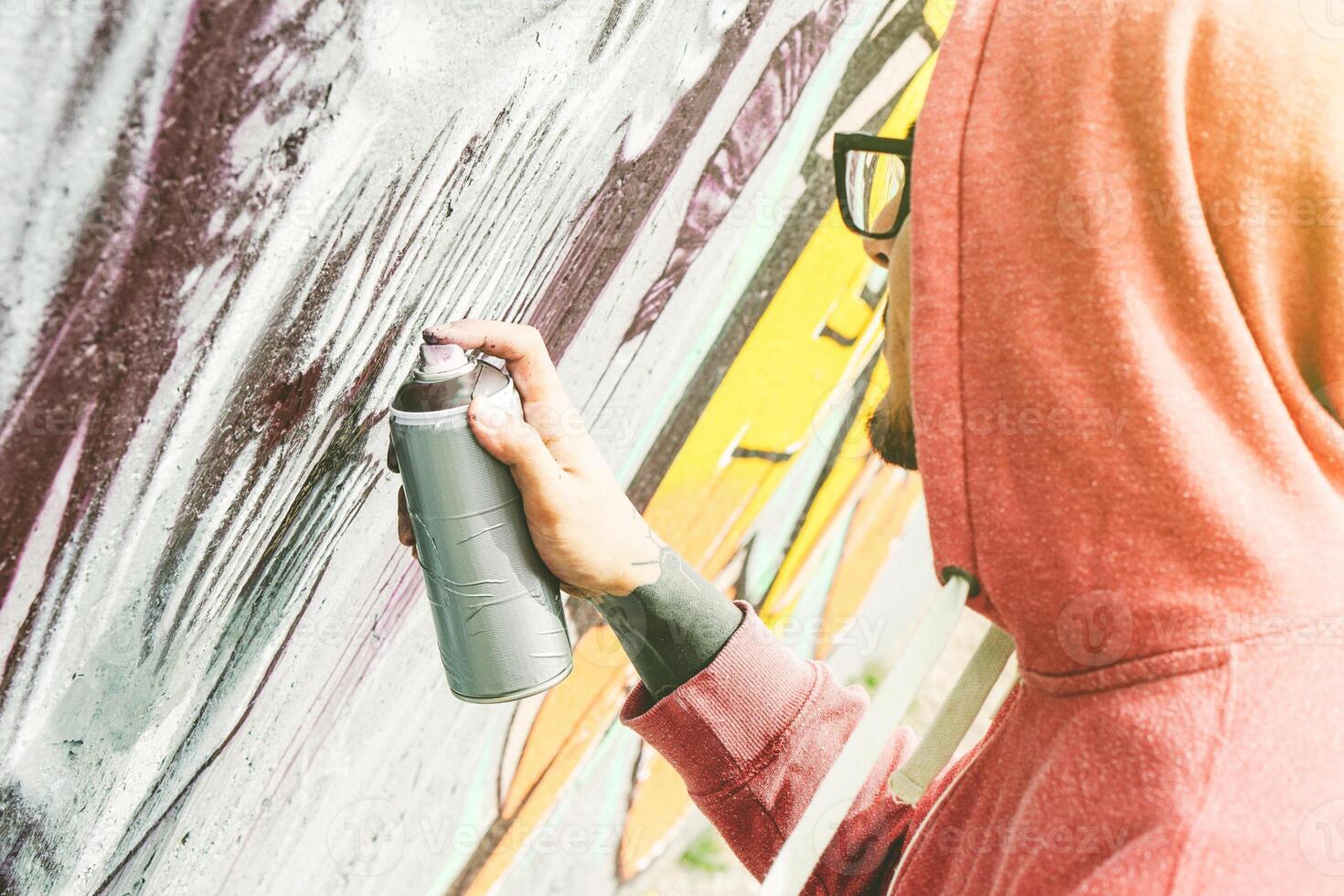 Straße Künstler Gemälde Graffiti mit Farbe sprühen seine Kunst auf das Mauer - - jung Mann Schreiben und Zeichnung Wandbilder auf das Straße - - städtisch Lebensstil und zeitgenössisch Kunst Konzept foto