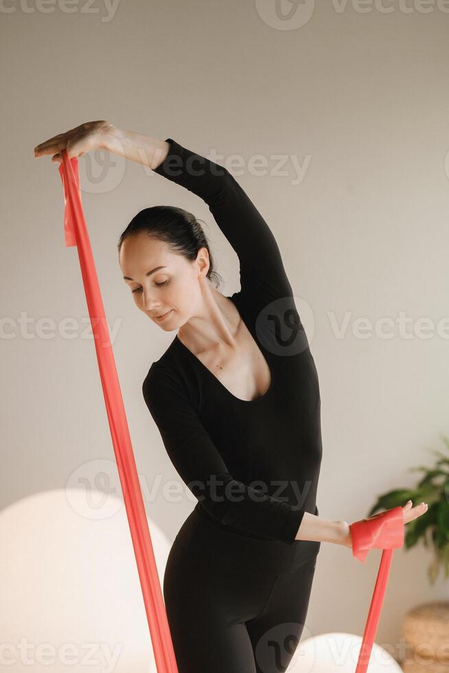 Mädchen im schwarz tun Fitness mit rot Bänder drinnen foto