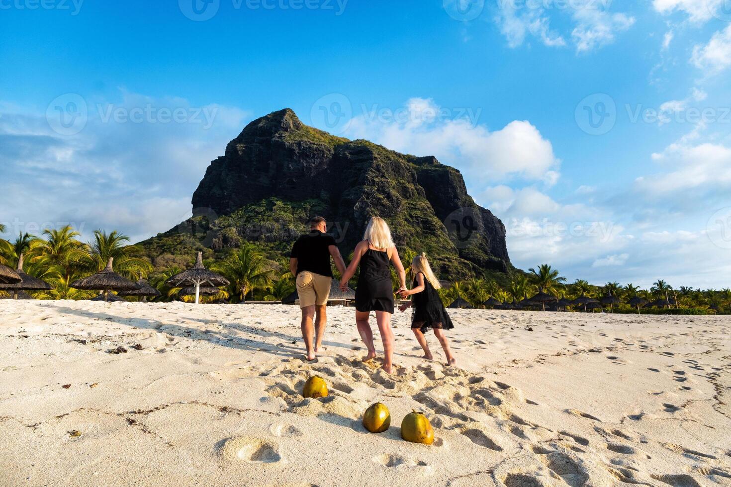 ein Familie von drei im schwarz Kleider auf das Weiß Strand von le Mourne auf das Insel von Mauritius. foto