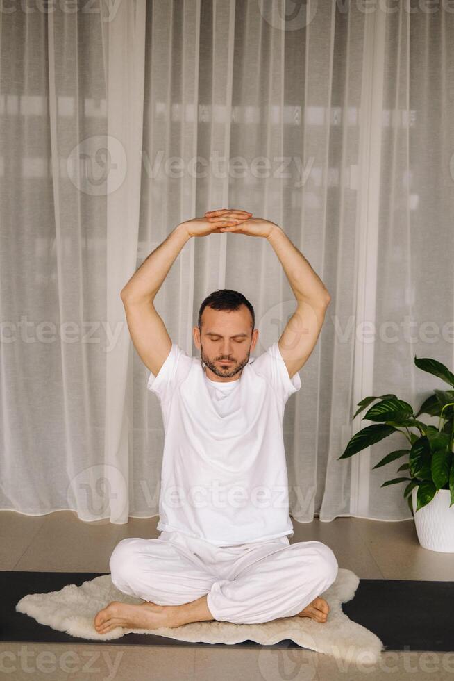 ein Mann im Weiß Sportbekleidung ist tun Yoga mit ein Fitness Zimmer. das Konzept von ein gesund Lebensstil foto