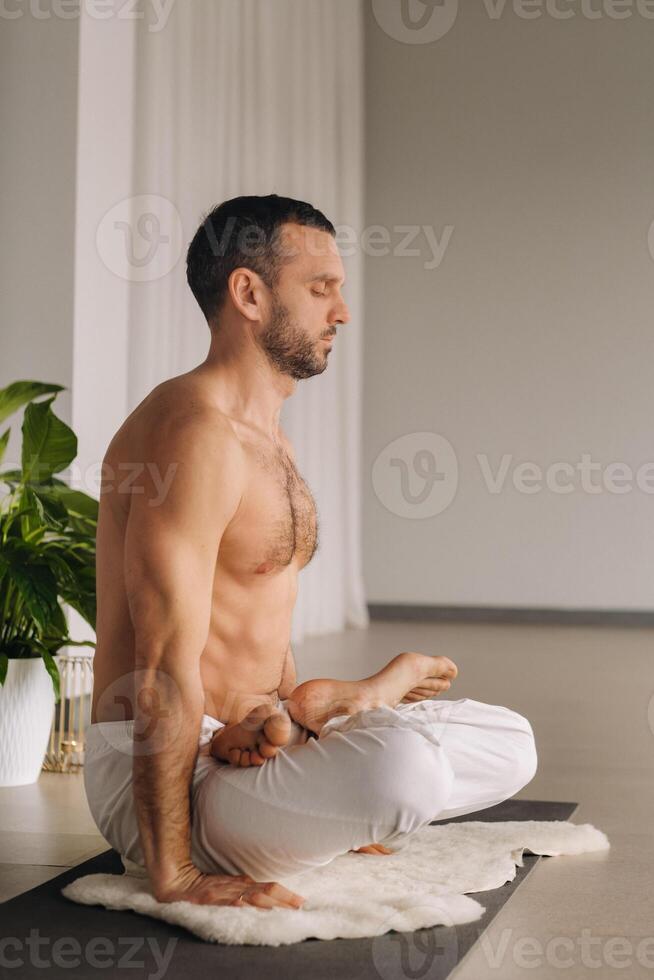 ein Mann mit ein nackt Torso tut Yoga im ein Fitness Zimmer. das Konzept von ein gesund Lebensstil foto