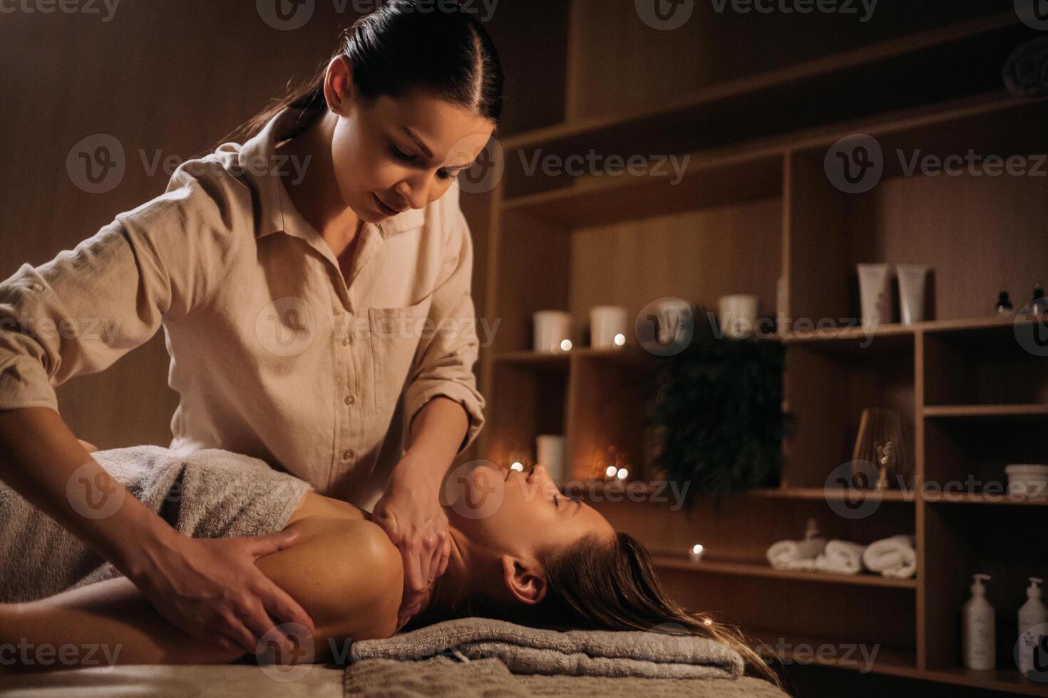 ein Masseuse gibt ein Körper Massage zu ein Frau im ein Spa Center. ein Fachmann Masseur Massagen das Schulter von ein Mädchen Lügen im ein Spa Center foto