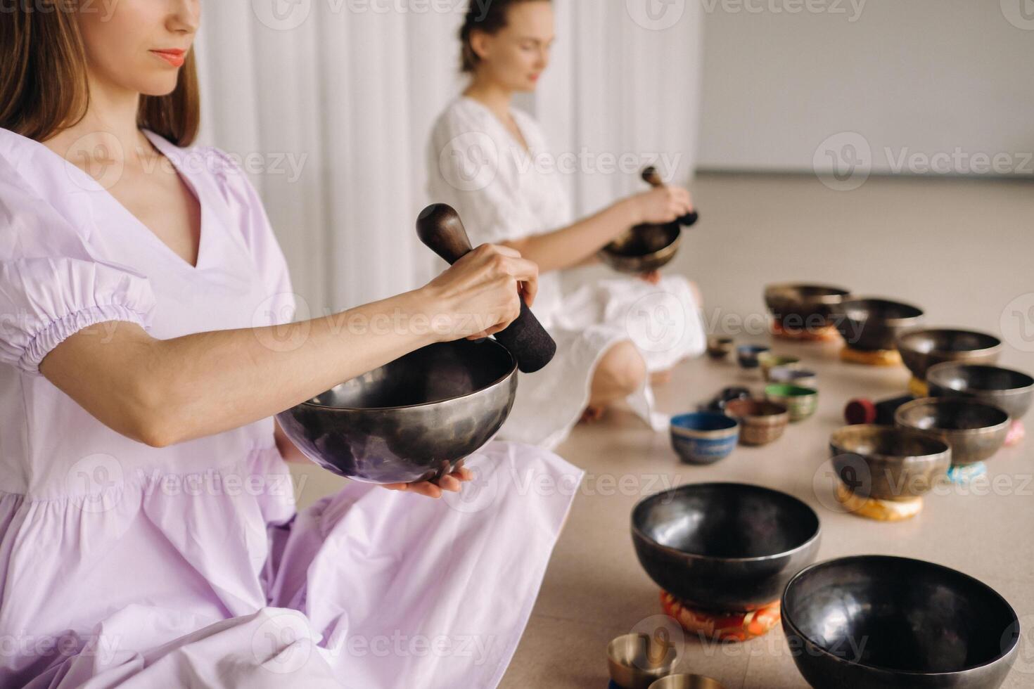 zwei weiblich Yoga Lehrer abspielen auf tibetanisch Schalen im das Fitnessstudio während ein Yoga Rückzug foto