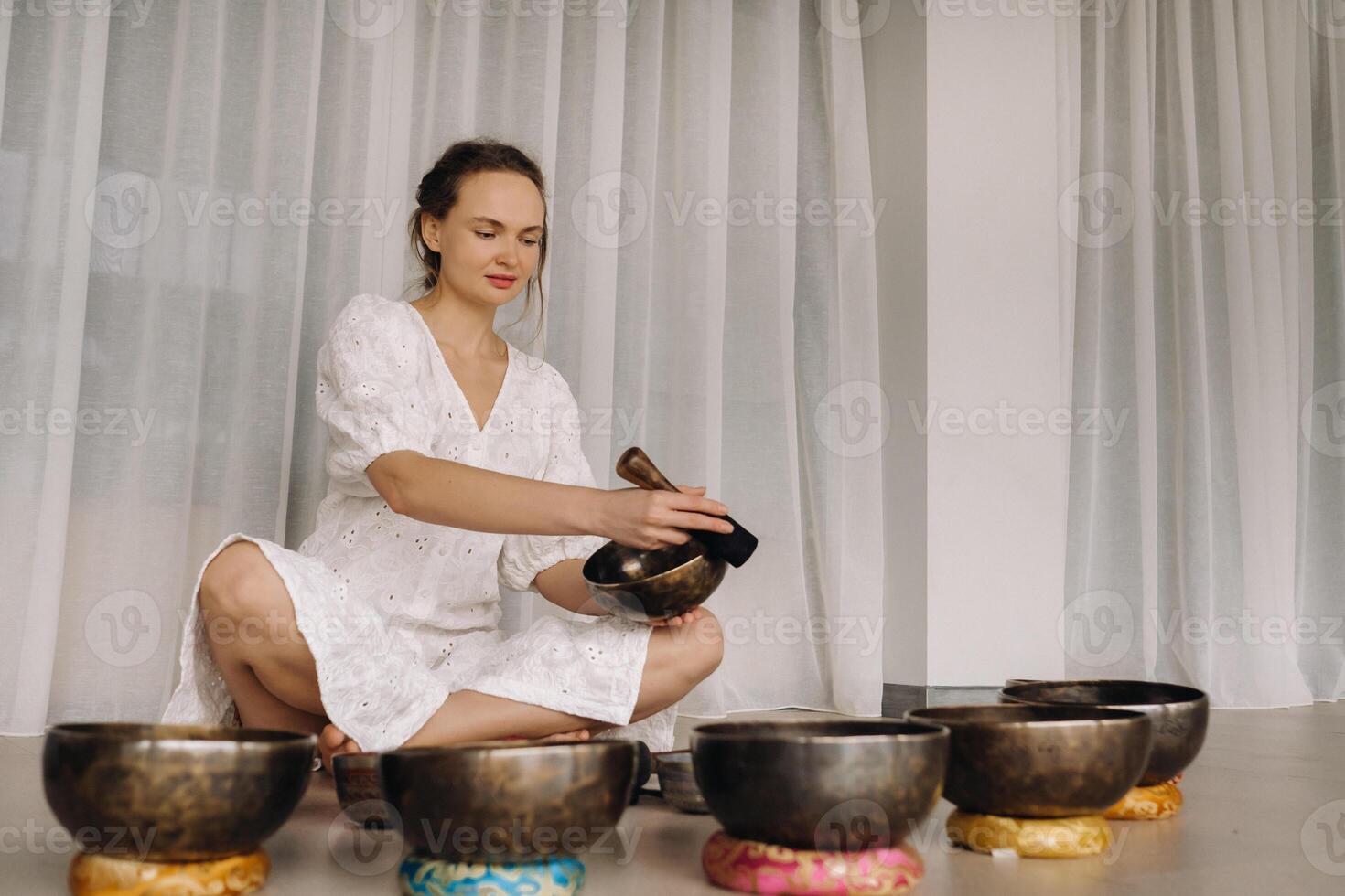 Porträt von ein weiblich Yoga Lehrer spielen ein tibetanisch Schüssel oder Singen ein Glocke im das Fitnessstudio während ein Yoga Rückzug foto