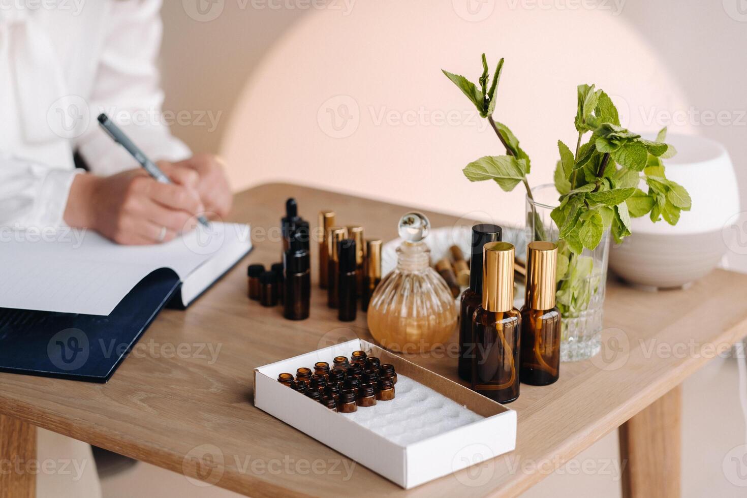 Nahansicht von weiblich Hände halten ein Flasche von wesentlich Öl und Schreiben ein Eintrag im ein Notizbuch, Aromatherapie foto